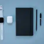 Des écouteurs sans fil compacts posés sur un espace de travail technologique épuré avec éclairage doux