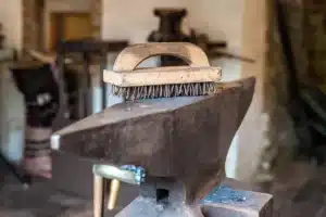 Intérieur d'une forge avec enclume, barres de métal et outils de forgeron sur établi en bois
