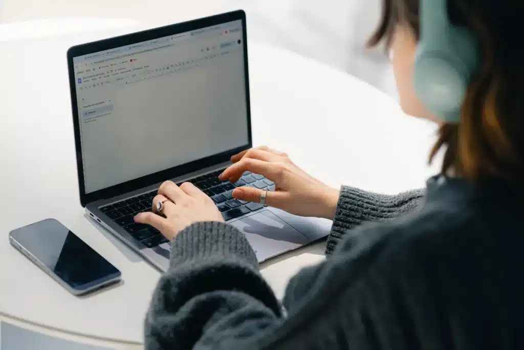 Mains anonymes composant un email sur un ordinateur portable avec plusieurs comptes ouverts
