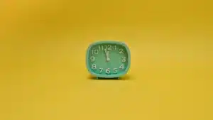 Réveil connecté circulaire sur une table de chevet avec affichage de l'heure et de la météo dans une chambre