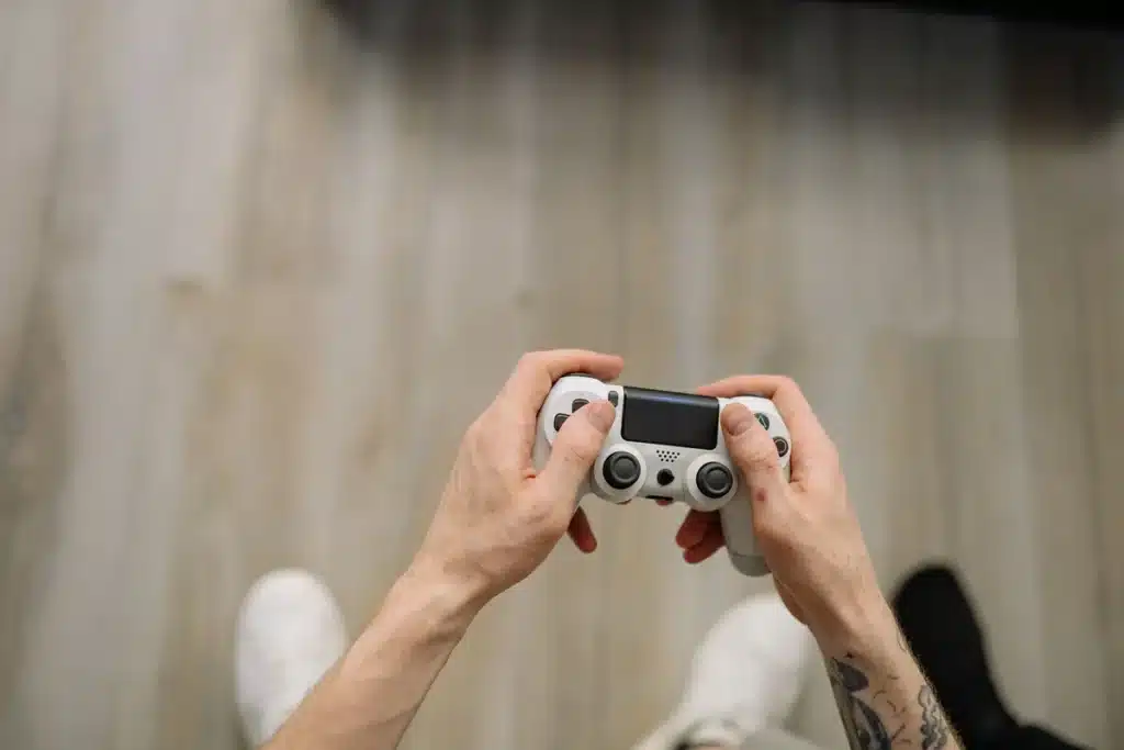 Mains d'un joueur tenant une manette de jeu dans une atmosphère sombre et tendue