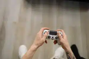 Mains d'un joueur tenant une manette de jeu dans une atmosphère sombre et tendue