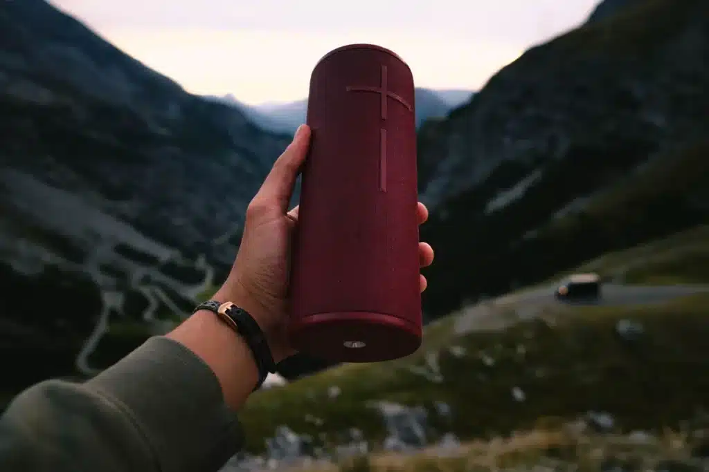 Une enceinte portable moderne posée sur une table en extérieur, baignée de lumière naturelle.