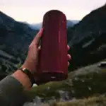 Une enceinte portable moderne posée sur une table en extérieur, baignée de lumière naturelle.