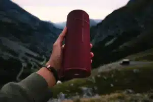 Une enceinte portable moderne posée sur une table en extérieur, baignée de lumière naturelle.