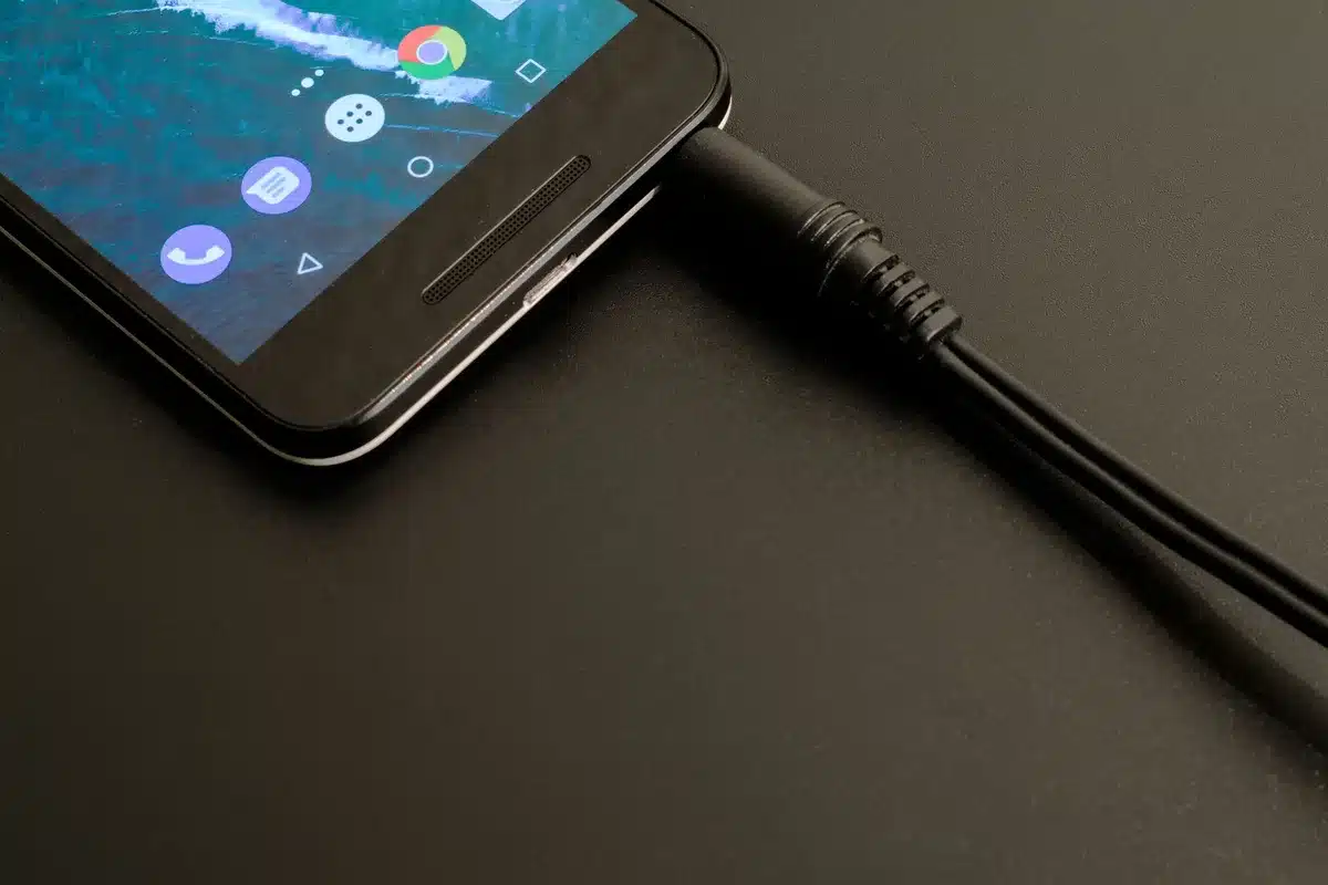 Casque audio en charge avec un câble USB sur une surface neutre