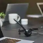 Casque audio posé sur un bureau avec un ordinateur portable et une tasse de café