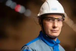 Ouvrier en usine portant un casque audio spatial, surveillant un bras robotique en mouvement