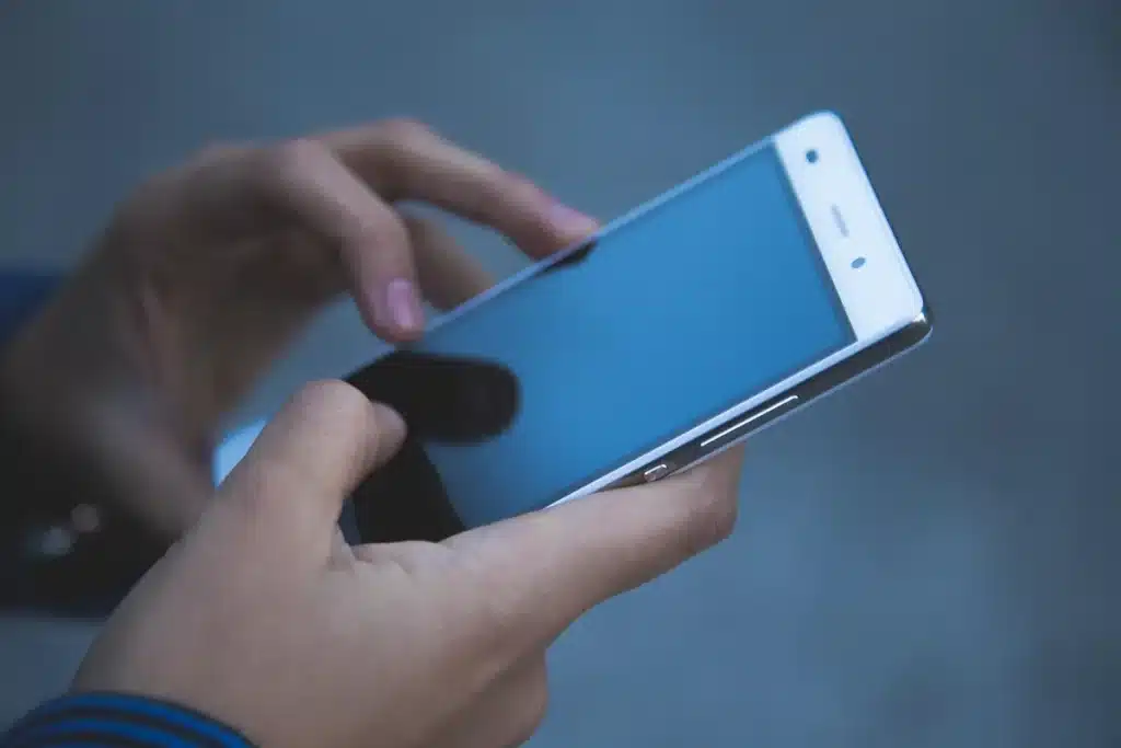 Mains ajustant les paramètres d'un assistant vocal sur l'écran d'un téléphone intelligent