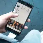 Smartphone posé sur une table en bois montrant une carte de sondage floue dans Messages, lumière du jour