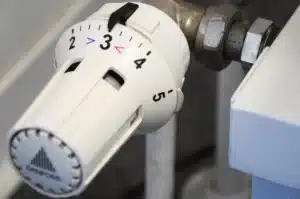 Main d'une personne ajustant un thermostat intelligent rond sur un mur intérieur