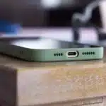 Main tenant un smartphone près d'un écran flou affichant un lecteur vidéo