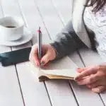Deux smartphones pliables anonymes posés sur une table de café à côté d'un carnet