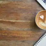 Deux écouteurs sans fil et un iPhone posés sur une table de café en pleine journée