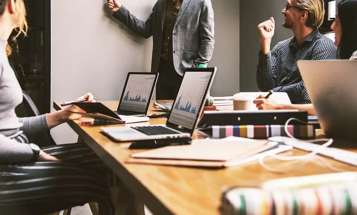 Équipe de développeurs en réunion autour d'une table de travail, discutant d'un projet de jeu