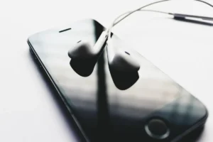 Mains tenant des enceintes connectées et des écouteurs avec des étiquettes de réduction