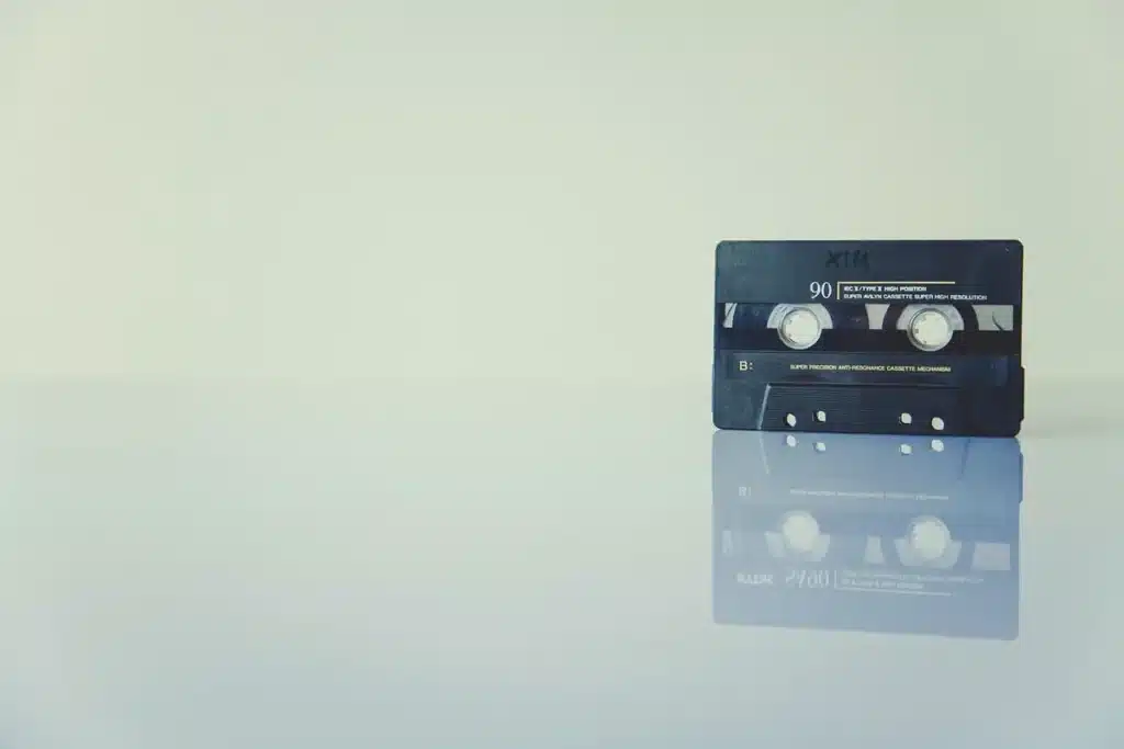 Lecteur cassette ouvert sur une table en bois, mains anonymes et cassettes empilées