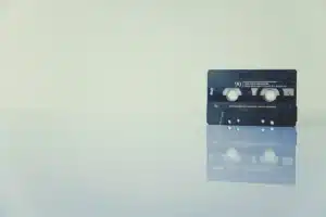 Lecteur cassette ouvert sur une table en bois, mains anonymes et cassettes empilées