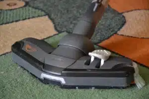 Robot aspirateur noir en train de s'accrocher à sa station de vidage blanche dans un salon lumineux