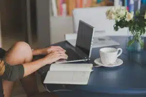 Main d'une personne tapant sur un clavier d'ordinateur portable avec une interface de chat visible à l'écran