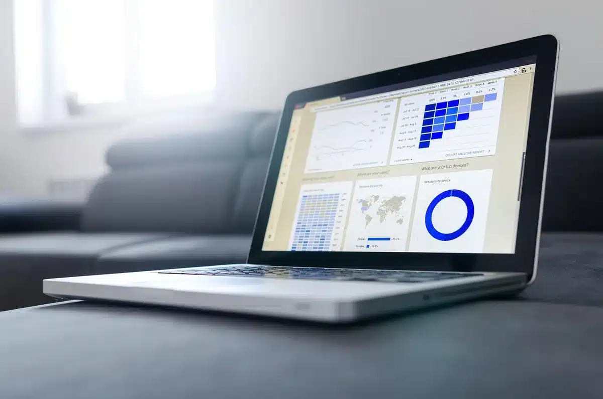 A brightly lit office desk with a laptop open on a business dashboard and a notepad showing handwritten tasks; no logos, no identifiable people