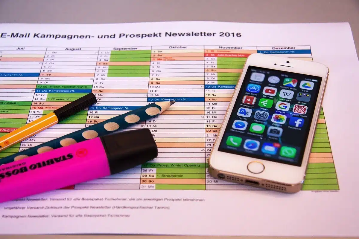 Two anonymous colleagues discussing a printed operations schedule at a meeting table, one pointing at a highlighted line; bright meeting room, no logos