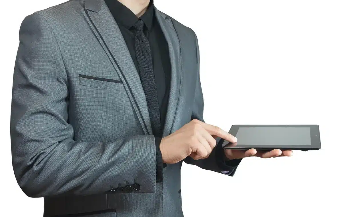 Close-up of hands holding a generic tablet on a plain store counter with a receipt and a small blurred price label in the background