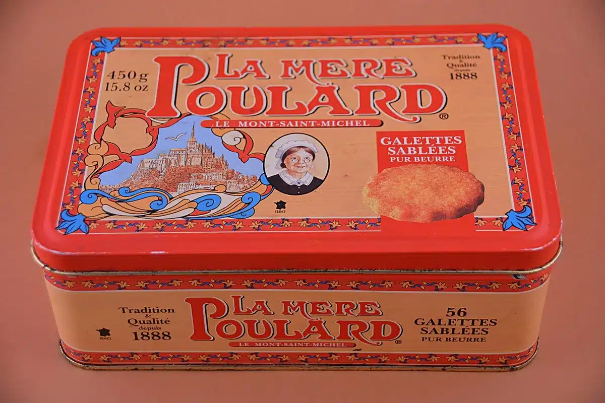 bright interior showing a generic product box on a table labeled only by a plain tag, with a blurred color desktop in background, hands reaching for the box
