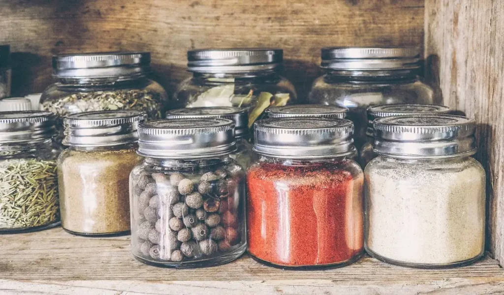Atelier en plein jour avec bocaux en verre, outils de jardinage et plantes séchant sur un établi