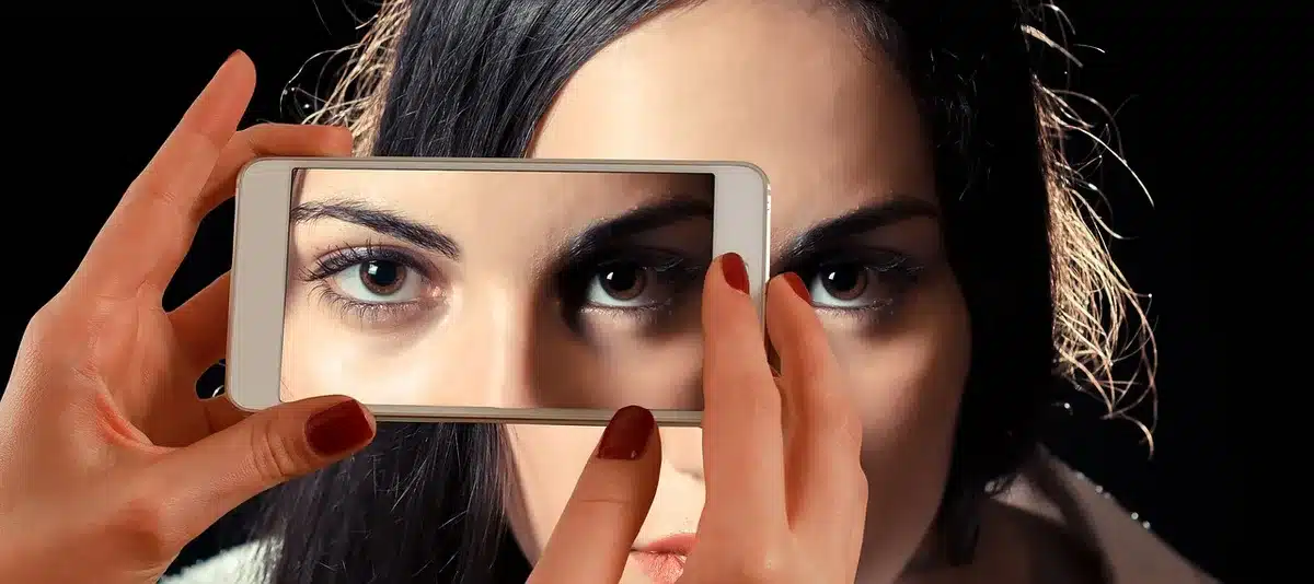 Close-up of an unbranded camera's rear LCD screen tilted out, showing a generic menu and a blurred indoor background, hands off-frame