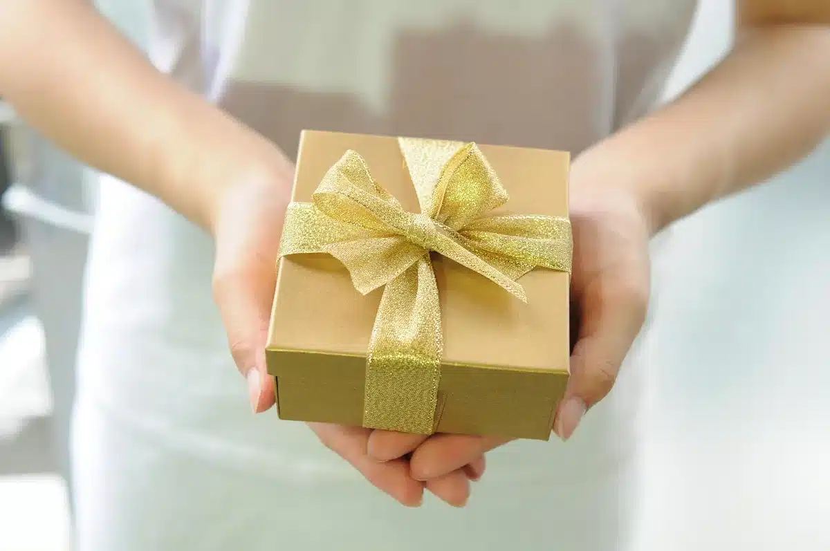 Hands placing an unbranded smartwatch into a small box on a tidy table, soft daylight, accessories laying flat and anonymous