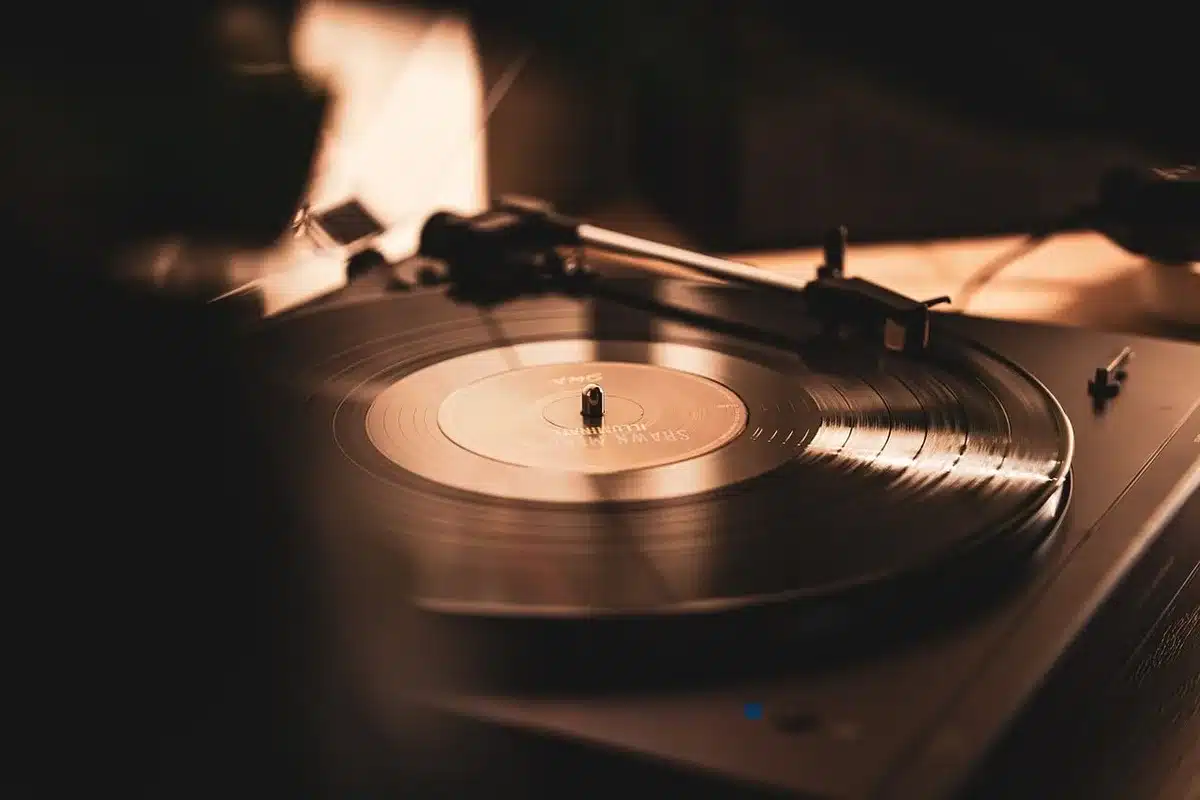 A tidy wooden turntable with a black felt mat and visible belt groove on the platter, sunlight on the edge of the plinth
