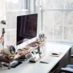 Mains d'un joueur sur manette et clavier devant un écran de jeu en pleine journée