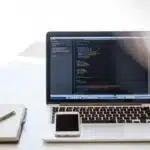 Bureau lumineux avec portable affichant code et mains sur le clavier