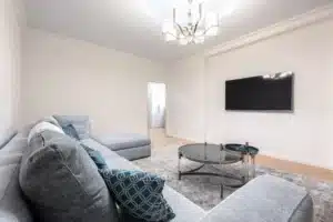 Télécommande moderne posée sur une table basse devant une TV allumée en plein jour