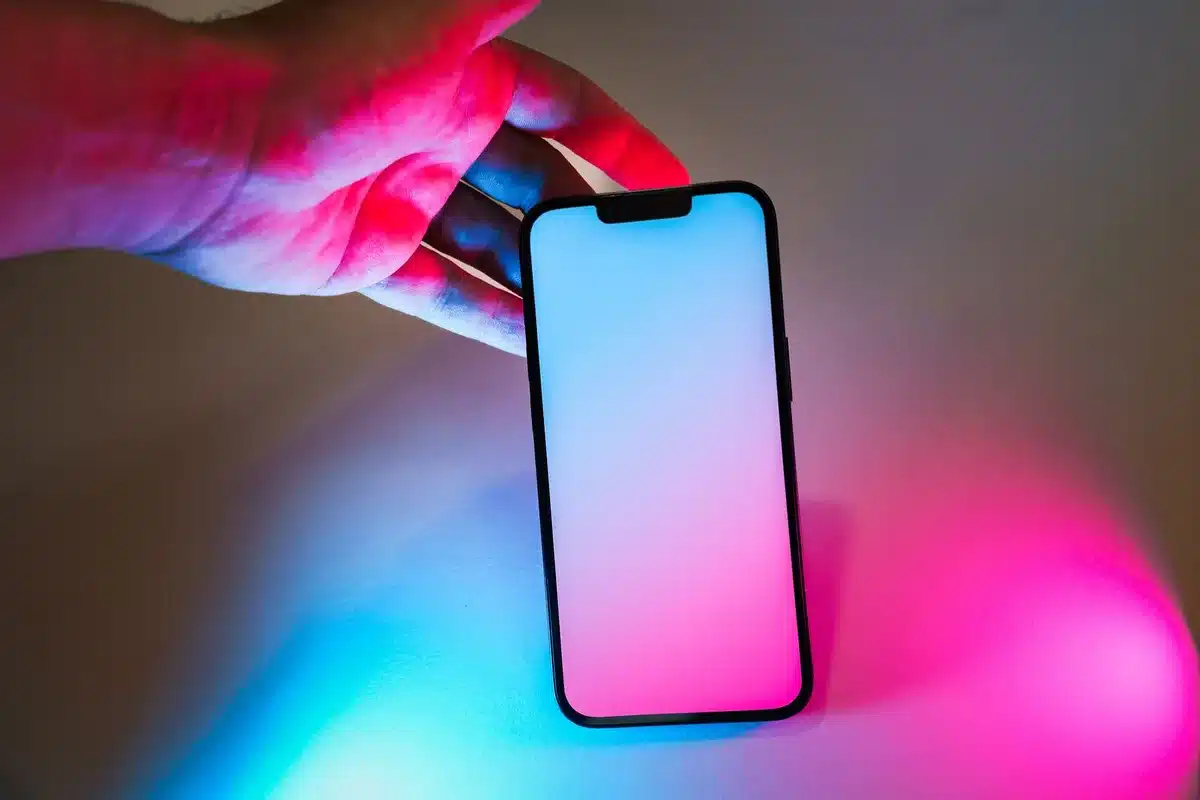 A clean retail display of a generic modern smartphone on a counter with a small price tag and blurred shelves in the background